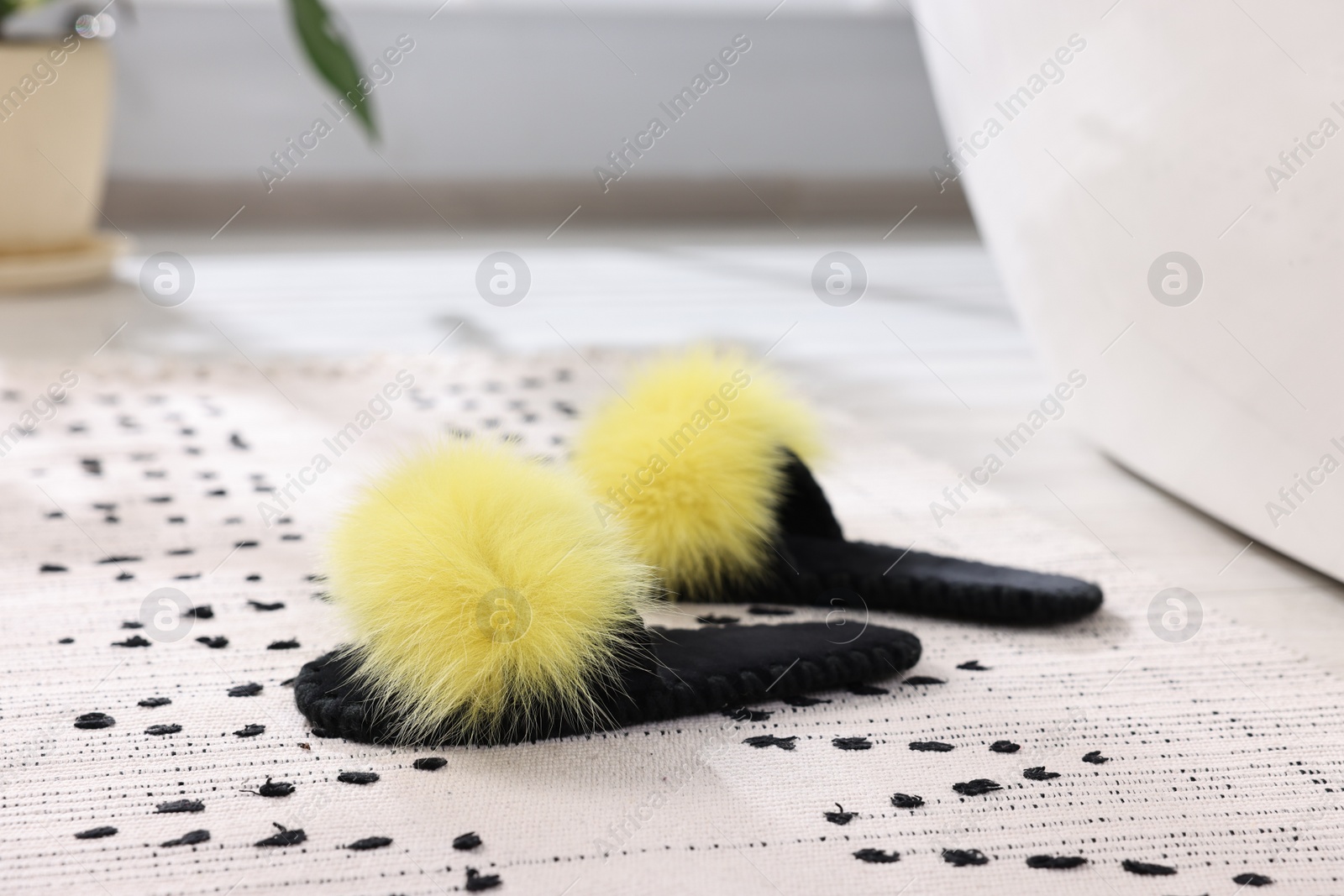 Photo of Fluffy slippers on carpet at home, closeup