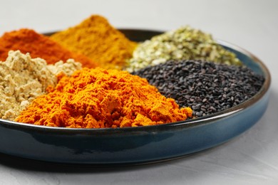 Plate with different spices on light grey table, closeup