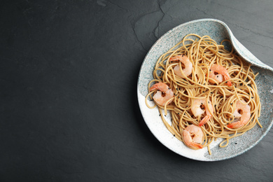 Photo of Plate of tasty buckwheat noodles with shrimps on black table, top view. Space for text