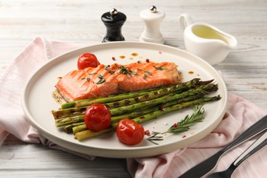 Photo of Tasty grilled salmon with tomatoes, asparagus and spices served on table, closeup