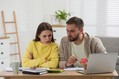 Photo of Young couple discussing family budget at table in living room