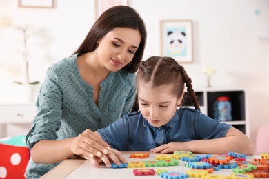 Photo of Young woman and little girl with autistic disorder playing at home