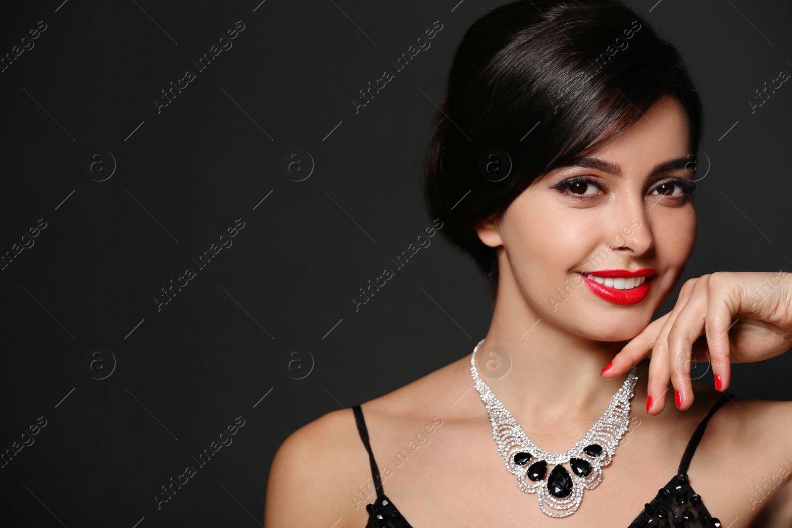 Photo of Beautiful young woman with elegant jewelry on dark background. Space for text