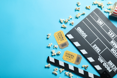 Flat lay composition with cinema tickets and clapperboard on light blue background, space for text