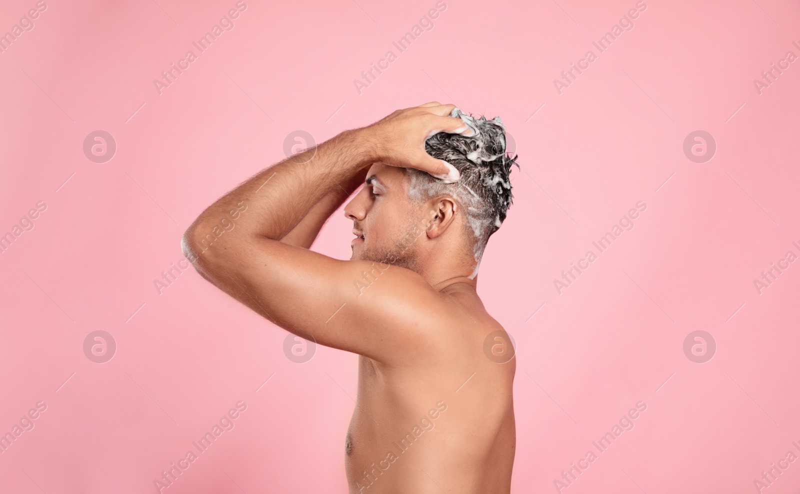 Photo of Handsome man washing hair on pink background