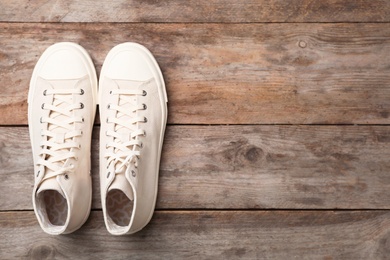 Photo of Pair of white sneakers on wooden background, top view