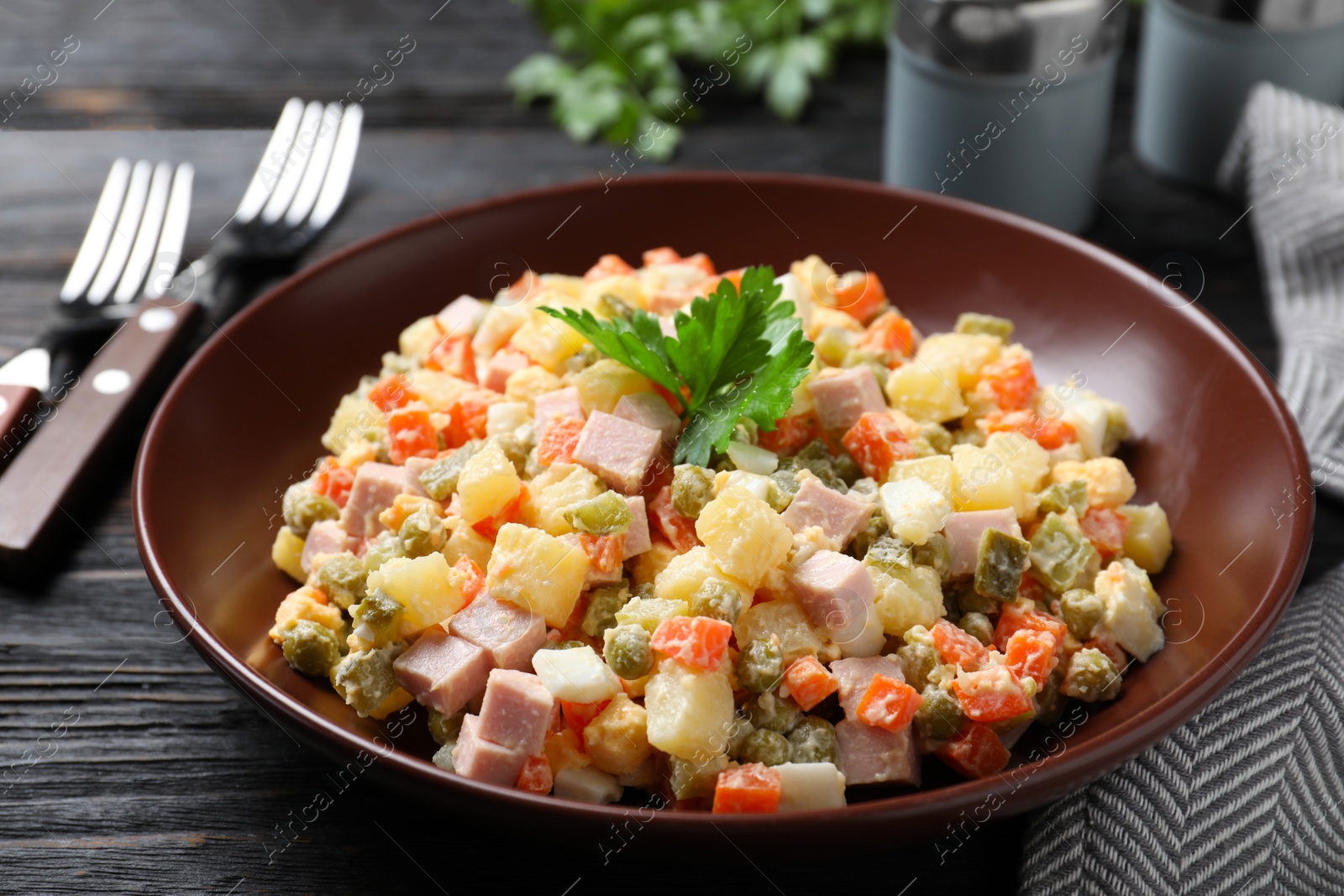 Photo of Delicious salad Olivier on black wooden table, closeup