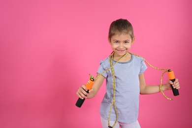 Photo of Cute girl with jump rope on color background. Space for text