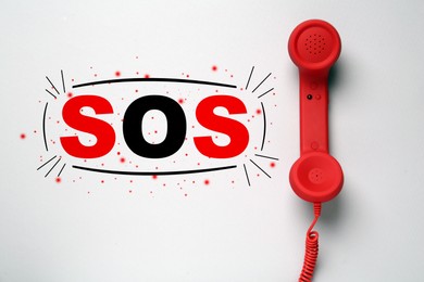 Telephone handset on light grey background, top view. Emergency SOS call