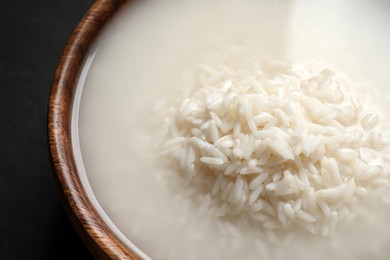 Photo of Rice soaked in water on black table, closeup