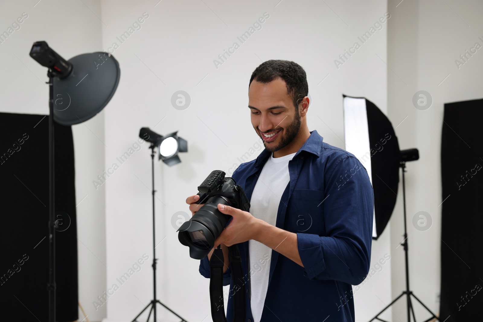 Photo of Young professional photographer with camera in modern photo studio, space for text