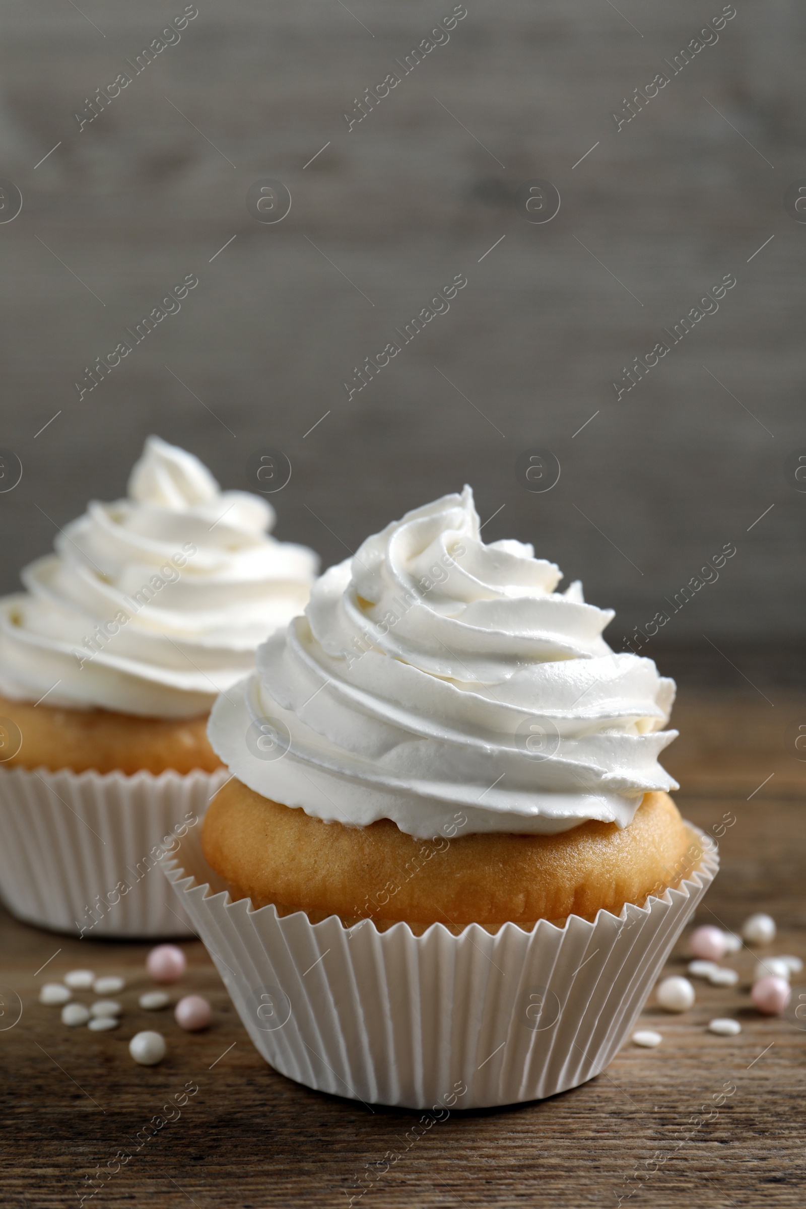 Photo of Delicious cupcakes with cream on wooden table