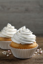 Photo of Delicious cupcakes with cream on wooden table