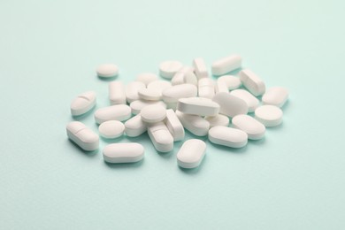 Pile of white pills on mint background
