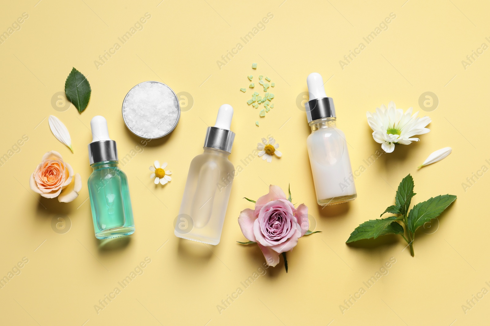 Photo of Flat lay composition with cosmetic serums on pale yellow background