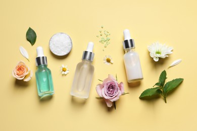 Flat lay composition with cosmetic serums on pale yellow background