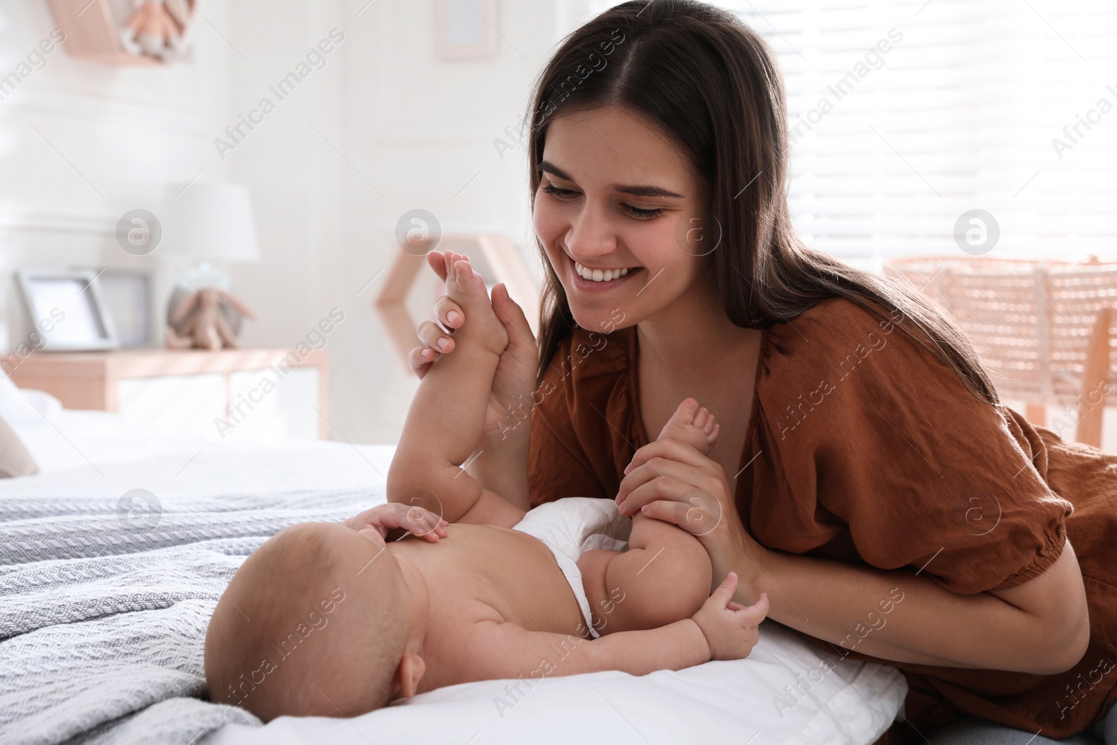 Photo of Mother with her cute baby on bed at home