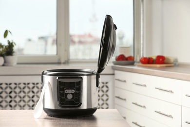 Photo of Modern multi cooker on table in kitchen. Space for text