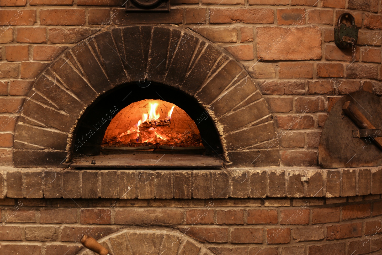 Photo of Brick oven with burning firewood and pizzas indoors