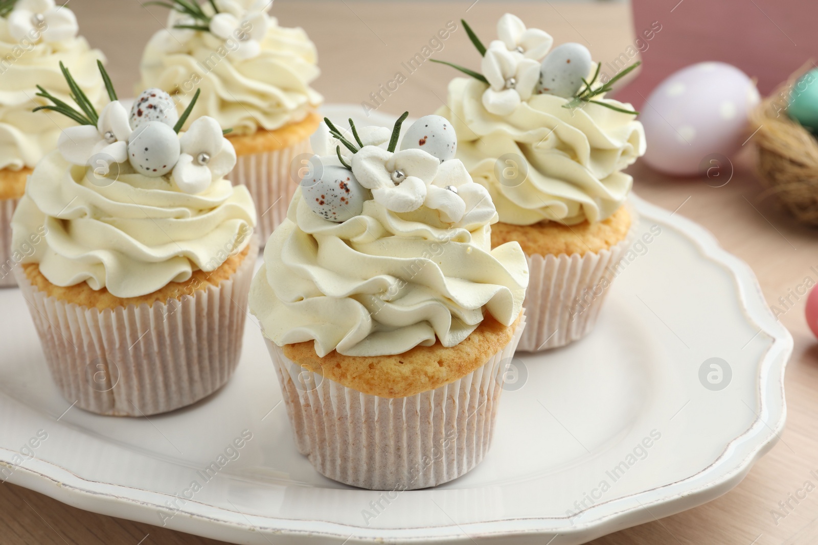 Photo of Tasty Easter cupcakes with vanilla cream on wooden table, closeup