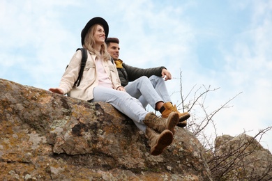 Photo of Couple of hikers sitting on steep cliff outdoors