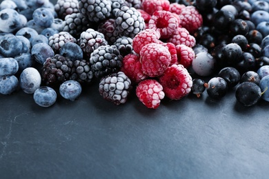 Photo of Mix of different frozen berries on black table, closeup