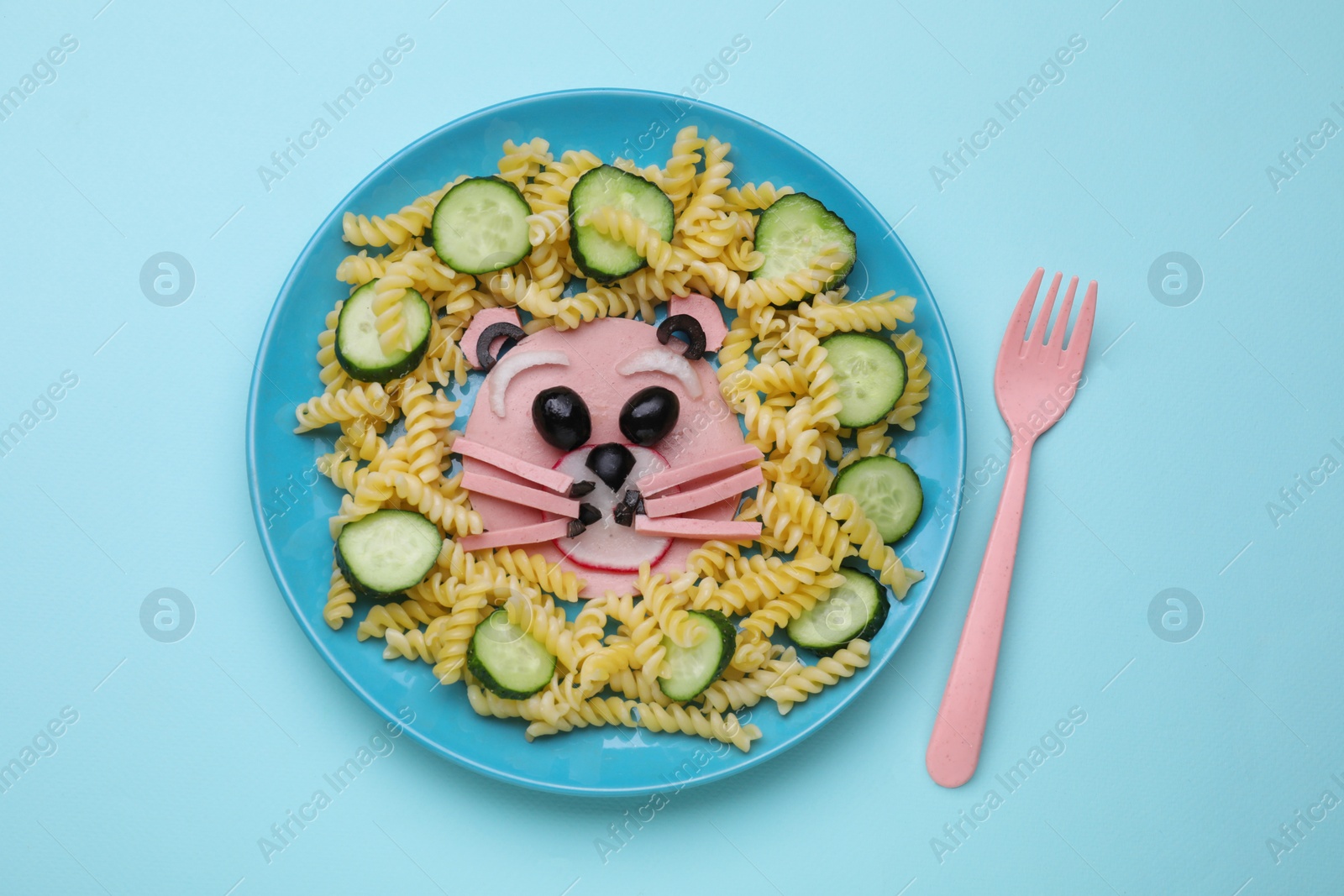Photo of Creative serving for kids. Plate with cute bear made of tasty pasta, vegetables and sausage on light blue background, flat lay