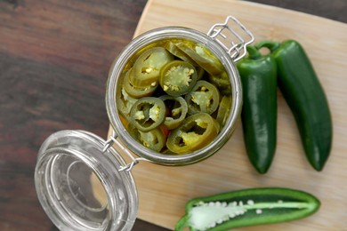 Photo of Fresh and pickled green jalapeno peppers on wooden table, top view