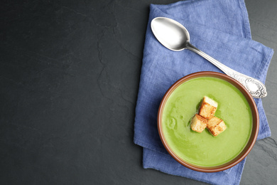 Delicious broccoli cream soup served on dark grey table, top view. Space for text