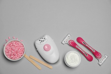 Photo of Modern epilator and other hair removal products on light grey background. Space for text