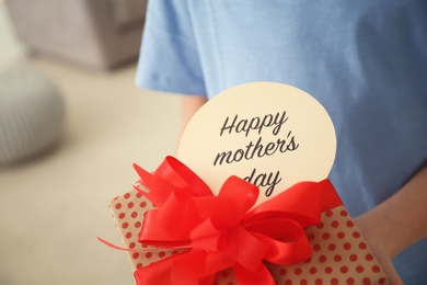 Photo of Little child with gift box for Mother's Day at home