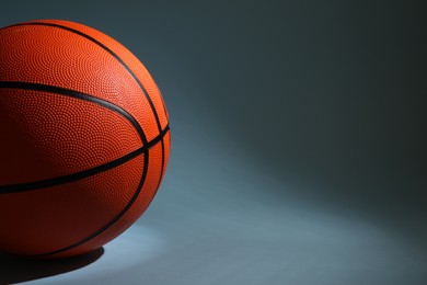 Photo of One orange basketball ball on dark grey background, closeup. Space for text