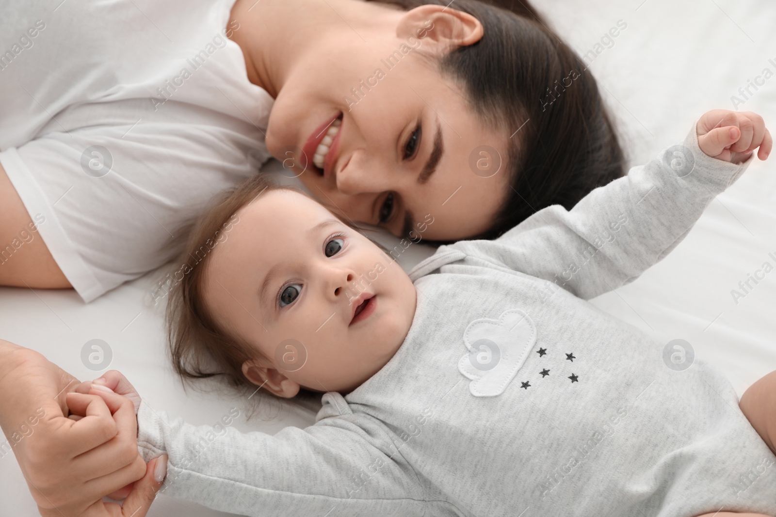 Photo of Portrait of mother with her cute baby lying on bed