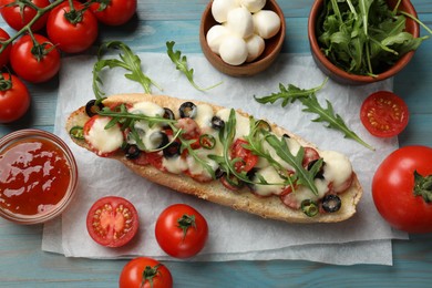 Photo of Tasty pizza toast and ingredients on light blue wooden table, top view