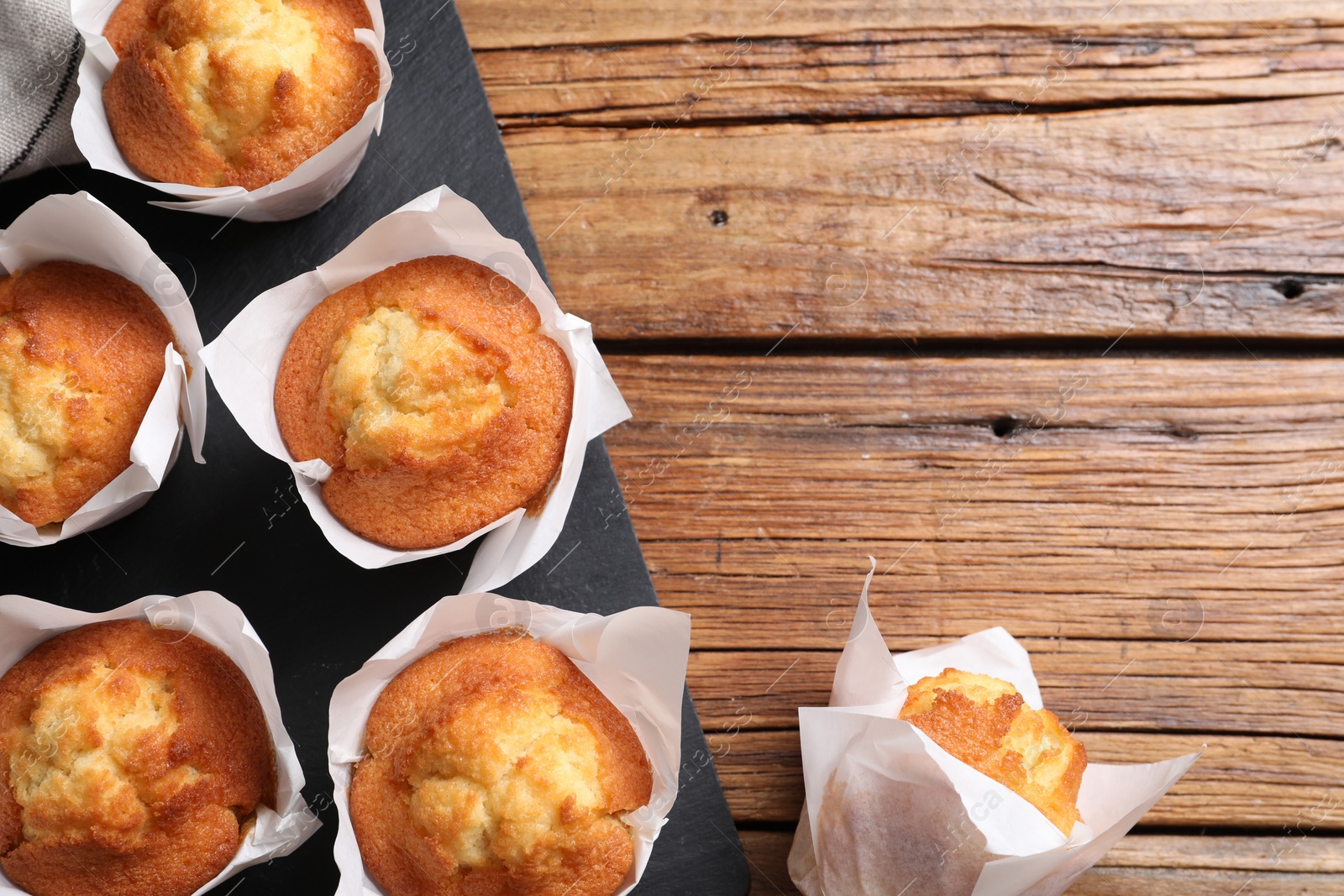 Photo of Delicious sweet muffins on wooden table, flat lay. Space for text