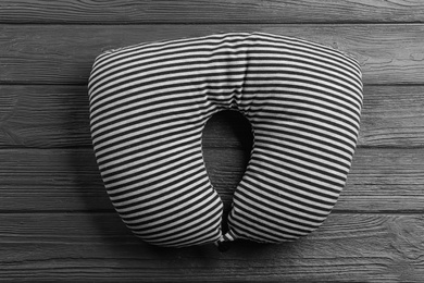 Striped travel pillow on wooden background, top view