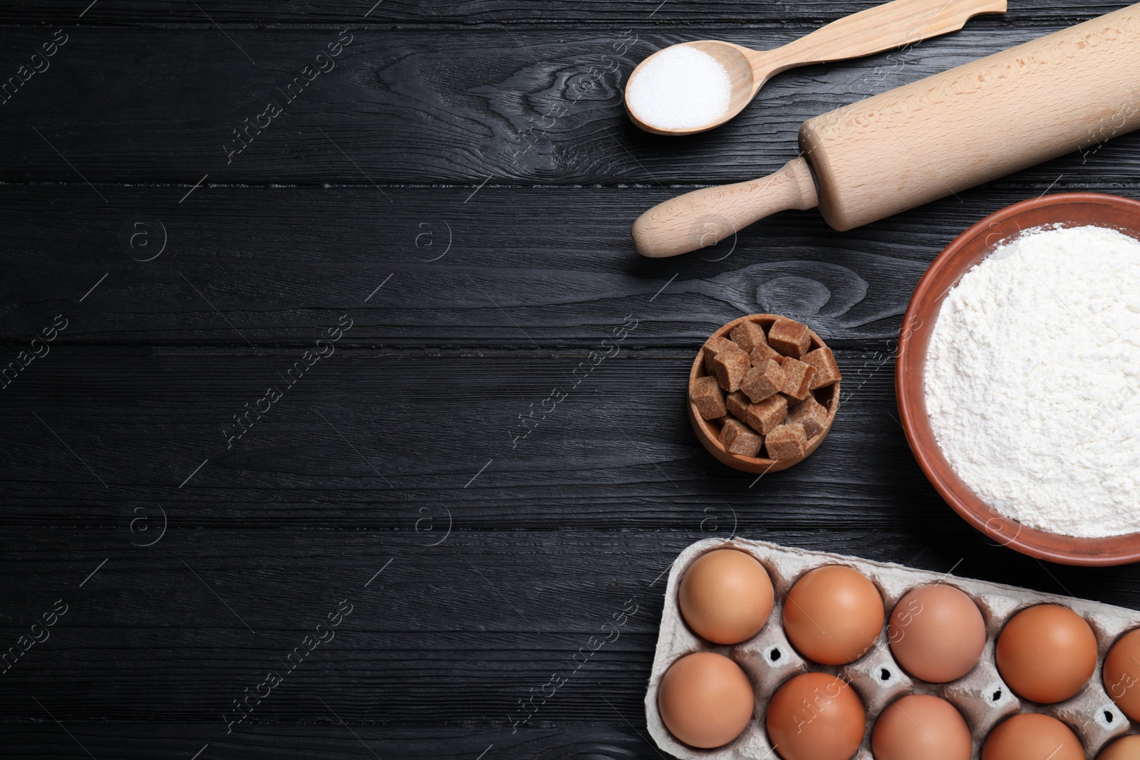 Photo of Cooking utensils and ingredients on black wooden table, flat lay. Space for text