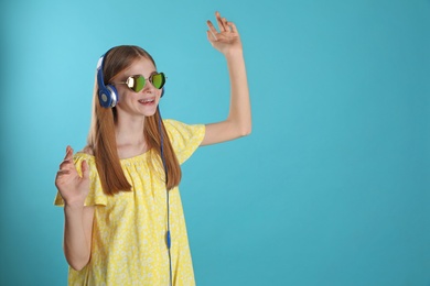 Photo of Teenage girl enjoying music in headphones on color background. Space for text