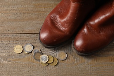 Poverty. Old boots and coins on wooden table, top view