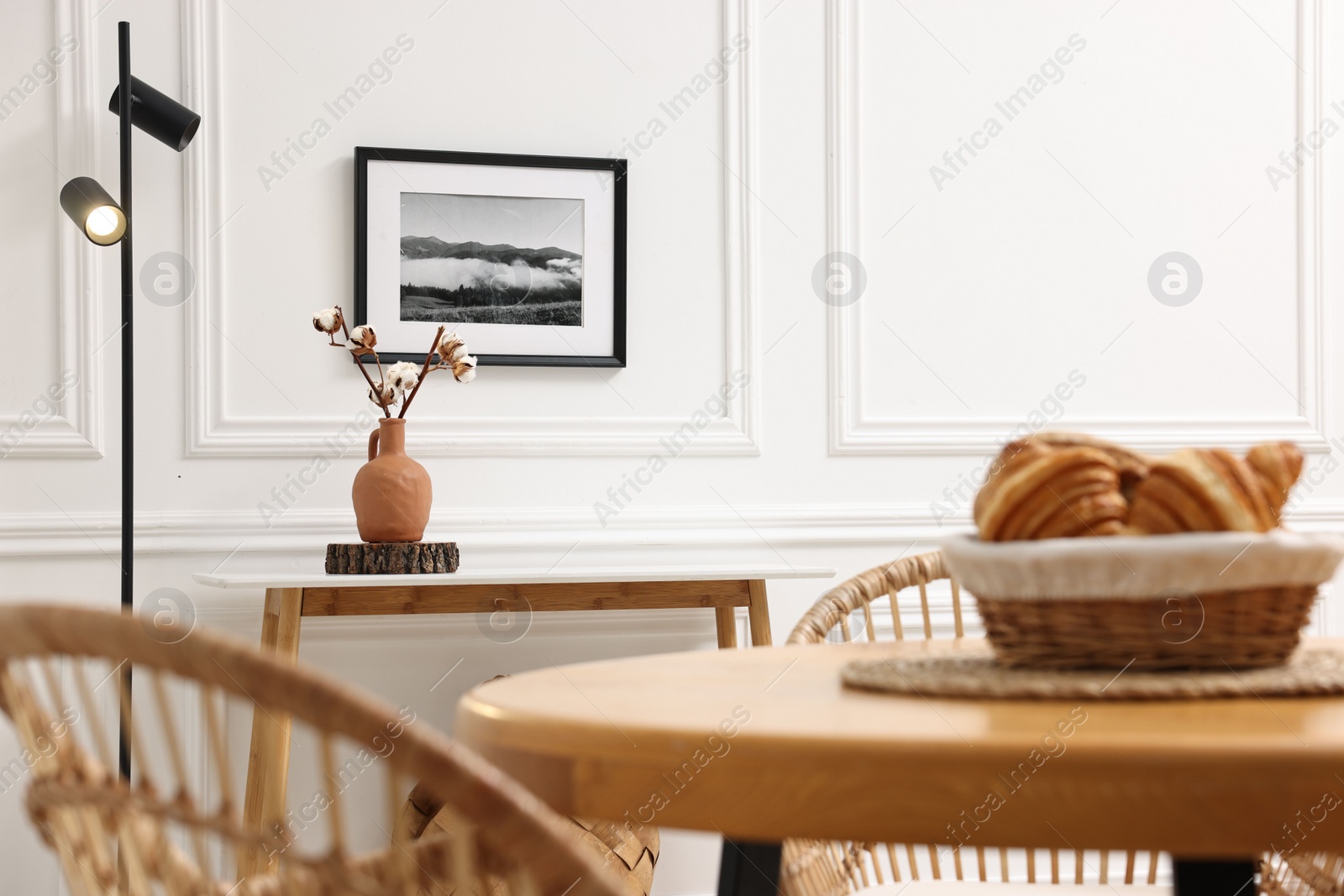 Photo of Tasty croissants on table and wicker chairs in dining room. Interior design