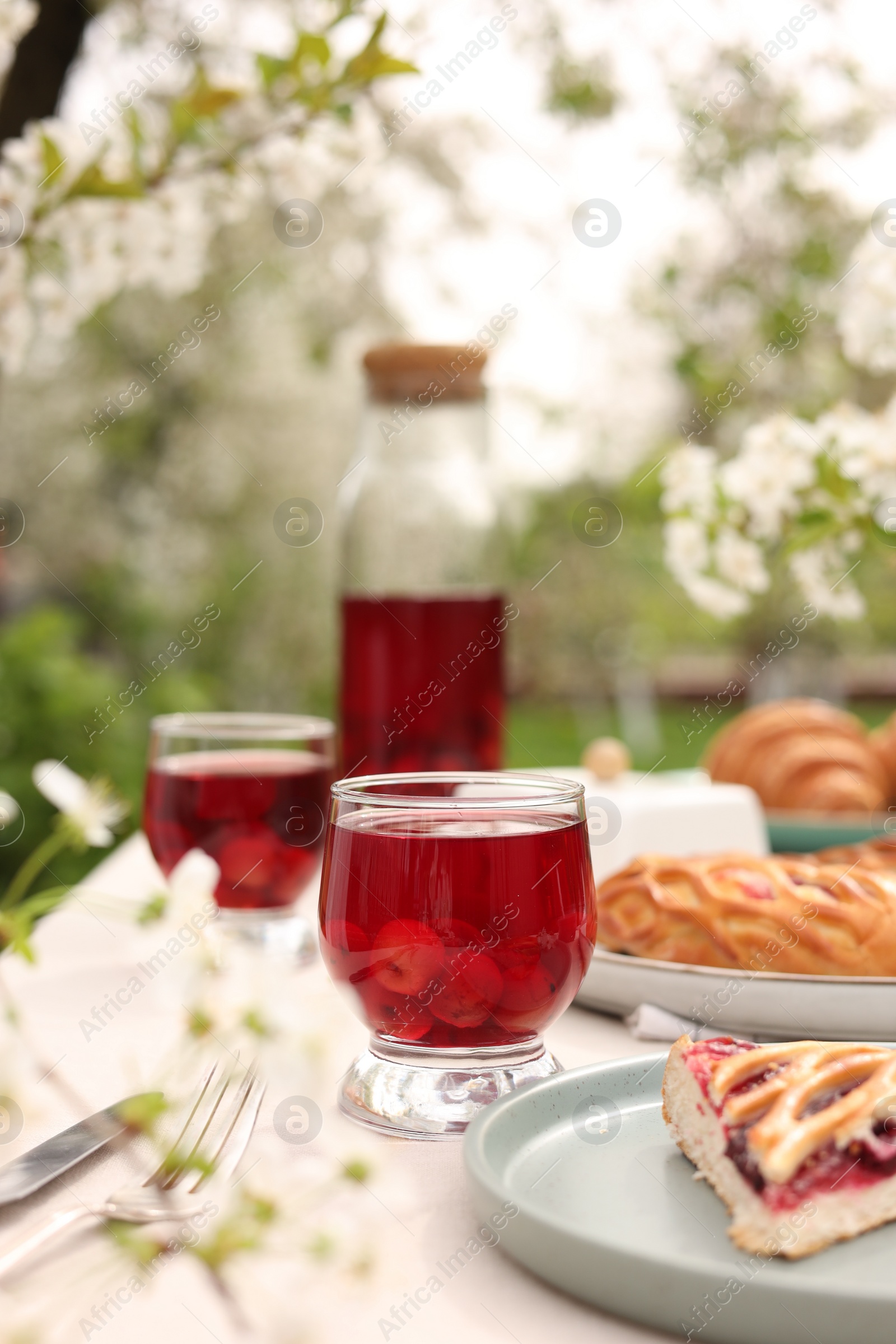 Photo of Stylish table setting with beautiful spring flowers, fruit drink and pie in garden