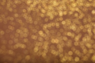 Blurred view of golden glitter on dusty rose background. Bokeh effect