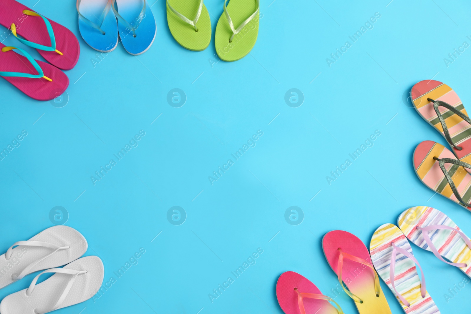 Photo of Different flip flops and space for text on blue background, flat lay. Summer beach accessories