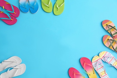 Photo of Different flip flops and space for text on blue background, flat lay. Summer beach accessories