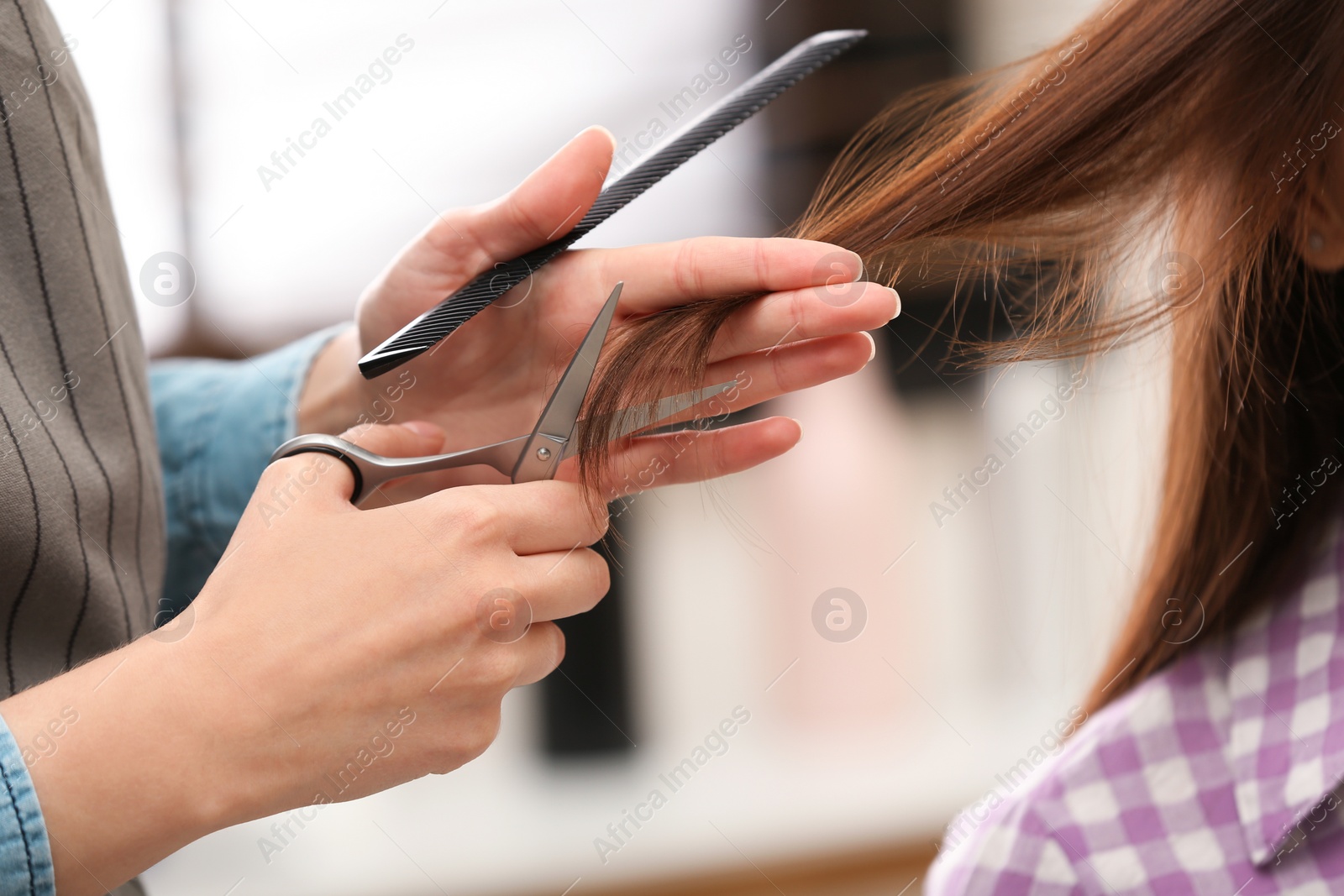 Photo of Barber making stylish haircut with professional scissors in beauty salon, closeup