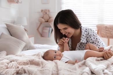 Photo of Mother with her cute baby on bed at home