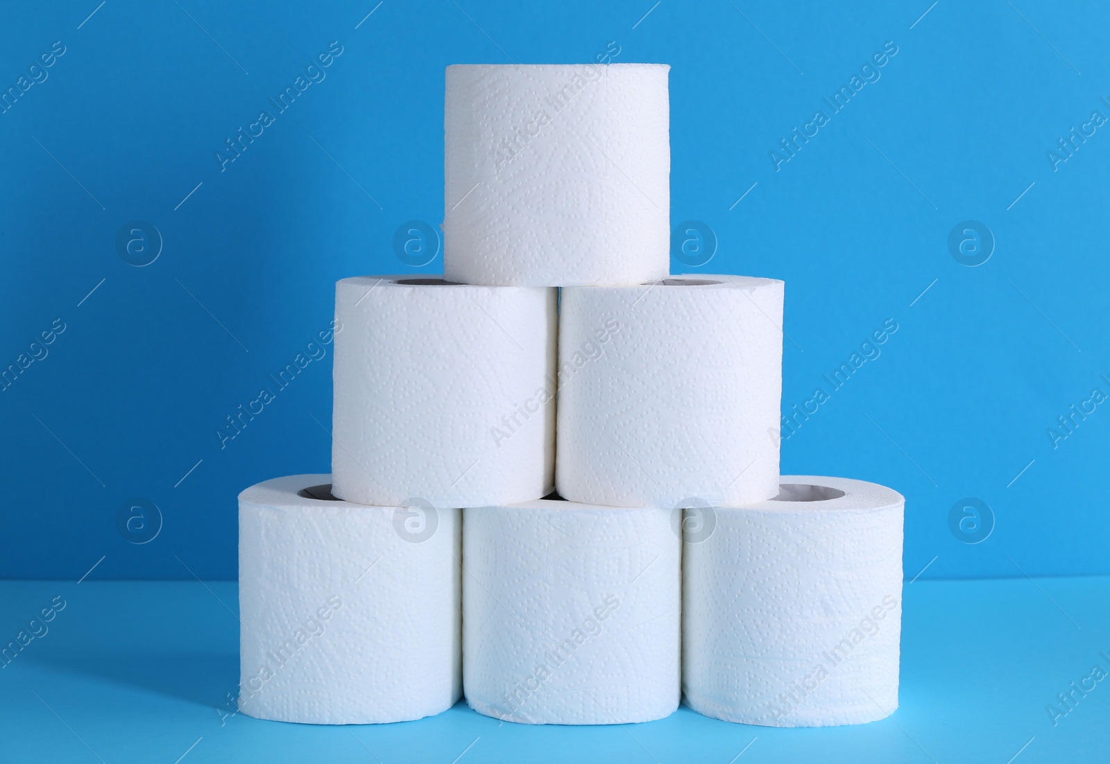 Photo of Pyramid of toilet paper rolls on light blue background