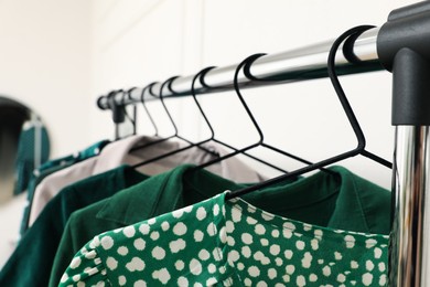 Rack with hanging clothes indoors, closeup. Interior design