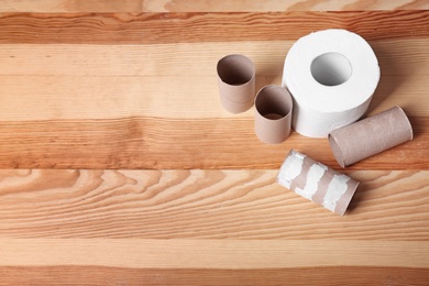Photo of Toilet paper roll and empty tubes on wooden background. Space for text