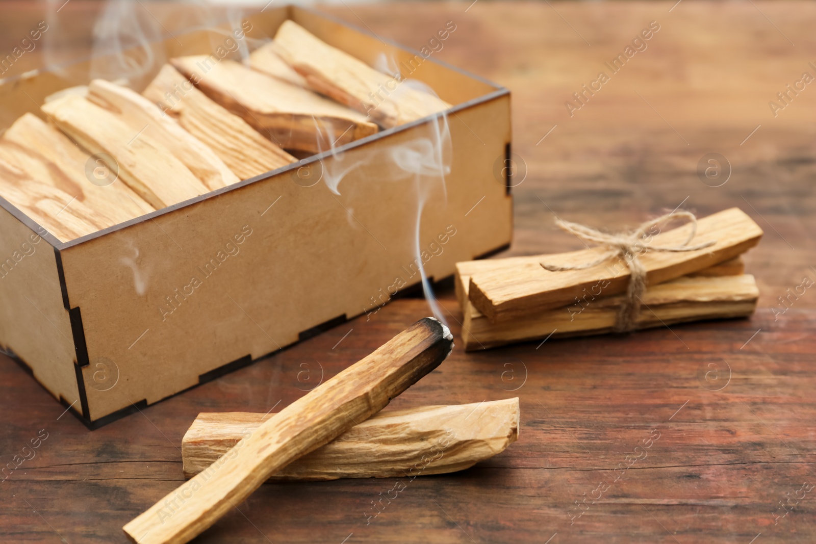 Photo of Many Palo Santo sticks and one smoldering on wooden table